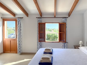 A bedroom with a bed, a window with a view, a door, and curtains. - Can Miquel, Traditional Villa with Private Pool (Son Proenç)