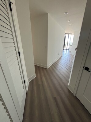 Ein Korridor mit Holzboden, weißen Wänden und einer Tür mit schwarzem Griff.