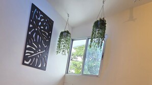 Ein Zimmer mit einem Bett, einem Fenster und hängenden Pflanzen.