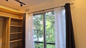 Ein Schlafzimmer mit einem Bett, einem Deckenventilator, einem Fenster mit Vorhängen und einem Holzschrank.