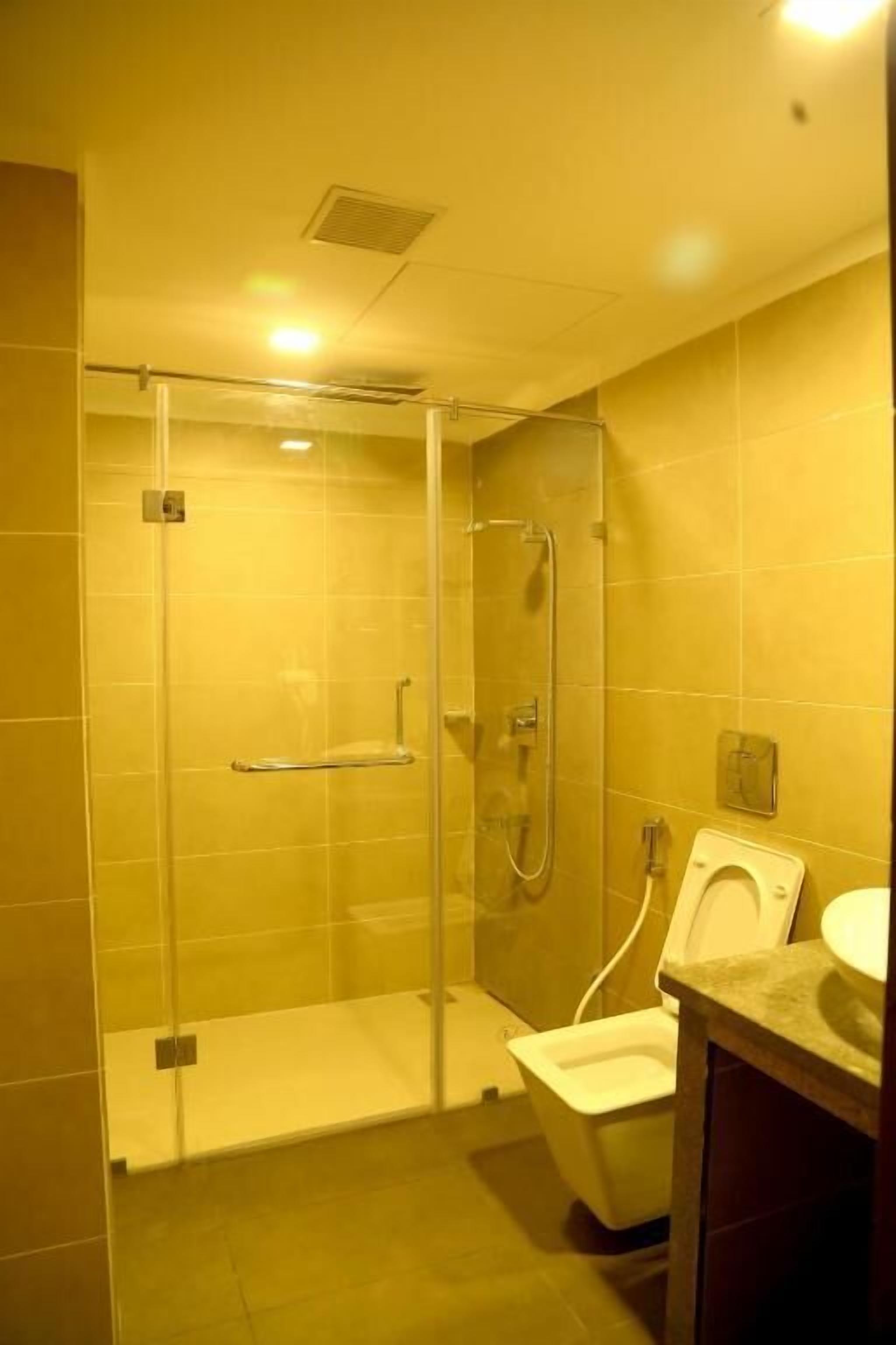 A bathroom with a glass-enclosed shower, a toilet, and a sink.