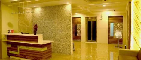 A modern lobby with a reception desk, a patterned wall, and a glossy floor.