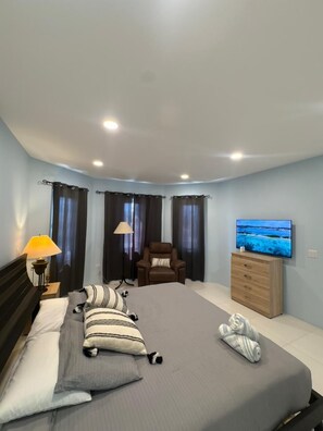 Ein Hotelzimmer mit Bett, Stuhl, Fernseher und Lampe.