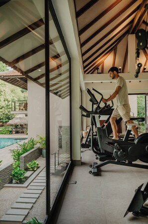 Ein modernes Fitnessstudio mit Glaswand, Laufband und Poolbereich im Freien sichtbar.