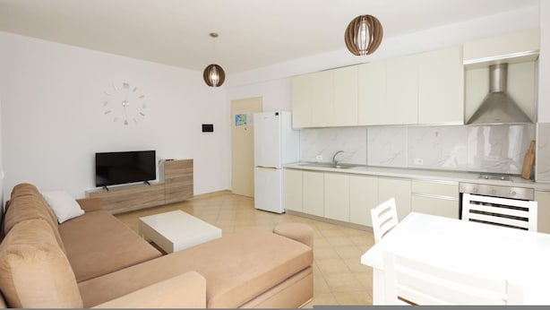 A modern living room with a sofa, TV, and dining area. - Lura Apartment 05 in Plazhi San Pietro (Ishëm)