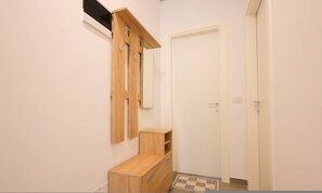 A small, clean room with a wooden bench, a door, and a wall-mounted shelf. - Sanpietro Vacation Apartment 052 (Ishëm)