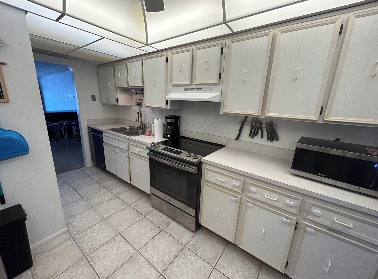 A kitchen with white cabinets, a stove, a microwave, and a dishwasher.
