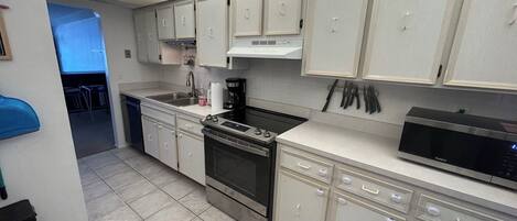 A kitchen with white cabinets, a stove, a microwave, and a dishwasher.