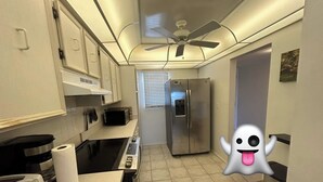 Eine Küche mit Mikrowelle, Herd, Kühlschrank und Deckenventilator.