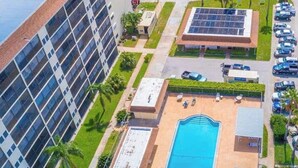 Ein Hotel mit Schwimmbad, Parkplatz und einem Gebäude mit Solaranlage.