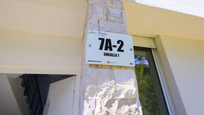 Eine Gebäudeecke mit einer Steinsäule und einem Schild mit der Aufschrift 'San Pietro 7A-2 SHKALLA 1'.