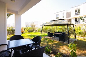 Ein Patio im Freien mit Tisch und Stühlen, ein überdachter Sitzbereich und Blick auf ein Wohngebäude.