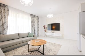 Ein modernes Wohnzimmer mit einer Couch, einem Couchtisch, einem Flachbildfernseher und einem weißen Schrank.