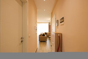 A hallway with a door, a wooden cabinet, and a sofa in the background. - Sanpietro Vacation Apartment 055 (Ishëm)