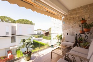 Ein Balkon mit Blick auf einen Garten, eine Steinmauer und Gartenmöbel.