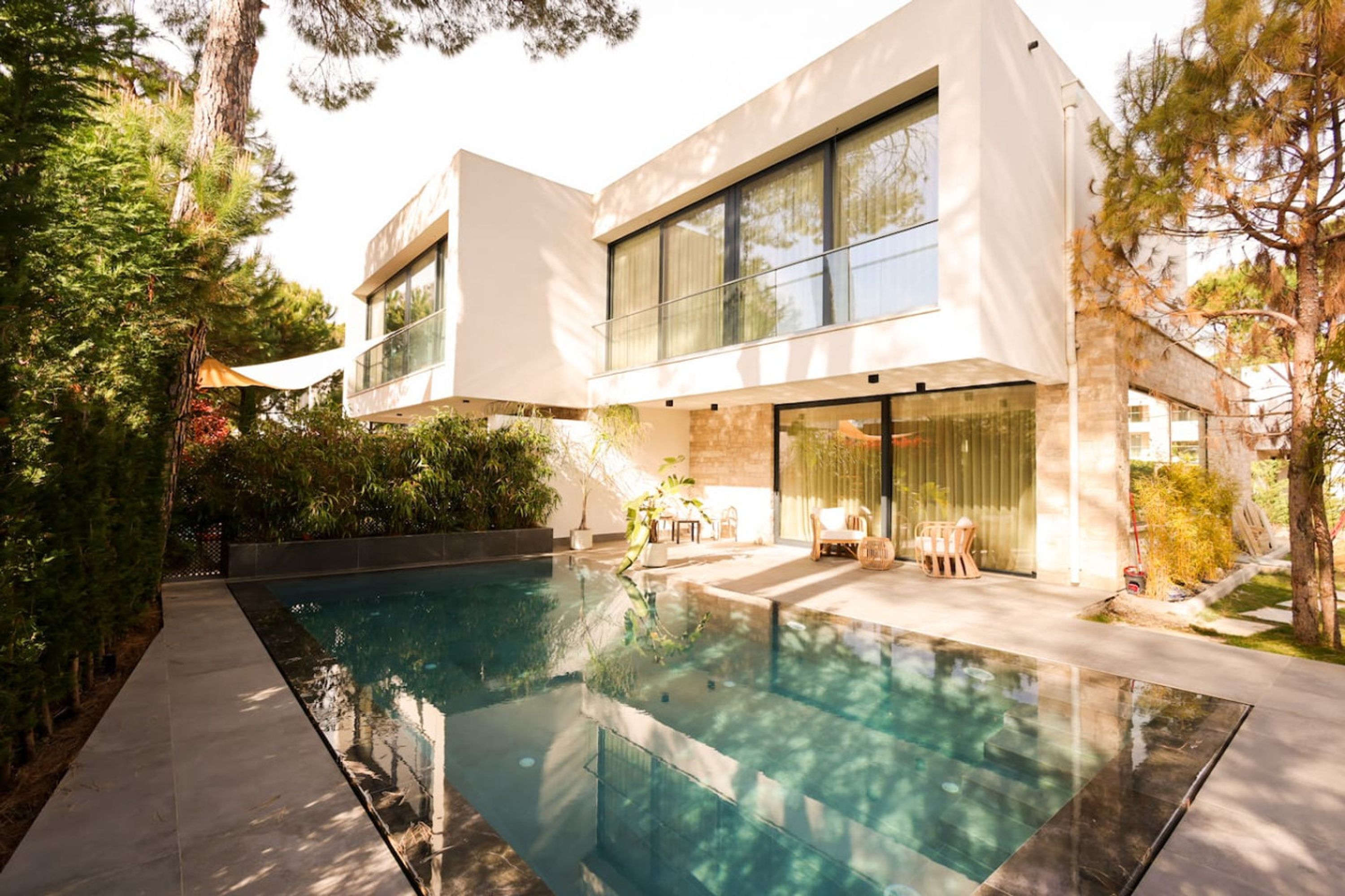 A modern house with a swimming pool, large windows, and a patio area.