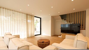 Una sala de estar moderna con un conjunto de sofá, un televisor y una escalera.