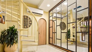 Un intérieur spacieux agr émenté d’un escalier en colimaçon, d’une grande porte en bois et d’un mur miroitant qui reflète un deuxième escalier.
