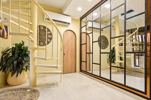 A spacious interior with a spiral staircase, a large wooden door, and a mirrored wall reflecting a second staircase. - Getsemani Rooftop Pool Paradise - Luxury 5BR (Cartagena de Indias)
