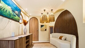 Un vestíbulo moderno con mostrador de recepción de madera, un sofá blanco, un televisor grande y un candelabro decorativo.