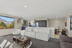 Ein modernes Wohnzimmer mit einem weißen Sofa, einem Couchtisch und einem Essbereich mit Tisch für zwei Personen.