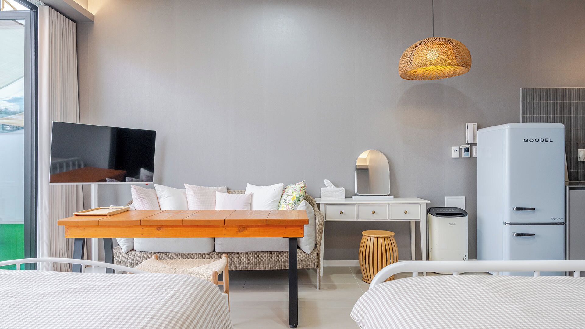 Una habitación de hotel moderna con cama, mesita de noche, televisión y una kitchenette con refrigerador.