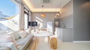 Um apartamento moderno com sofá, mesa de jantar, cozinha e televisão.