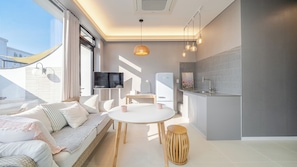 Un appartement moderne comprenant un canapé, une table à manger, une cuisine et un téléviseur.