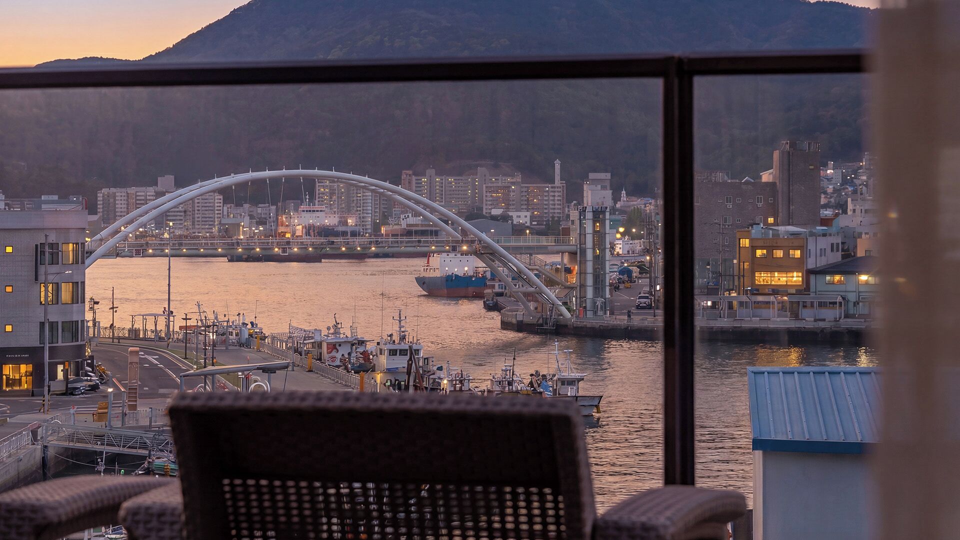 A view from a window overlooking a harbor with a bridge, boats, and buildings.