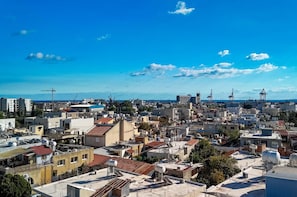 Un paysage urbain mêlant des immeubles résidentiels et commerciaux, un ciel bleu dégagé et, au loin, des grues signalant des travaux de construction.
