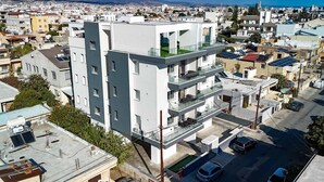 Un edificio de varios pisos con balcones, una terraza en la azotea y vistas panorámicas de la ciudad.