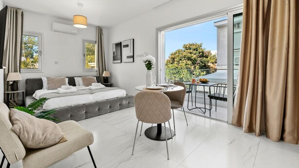 Una habitación de hotel moderna con cama, zona de estar y balcón con vistas.