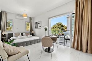 Een moderne hotelkamer met een bed, zithoek en een balkon met uitzicht.
