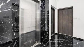 A modern elevator with a metallic finish, a wooden door, and a marble floor. - STYLE°Limassol 101 Two Bedroom by Ezoria Villas (Limassol)