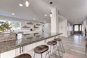 A modern kitchen with a large island, bar stools, and pendant lighting. - Stunning 6 Bdrm Desert Ranch Equestrian Estate w/Breathtaking Views! (Citrus Park)