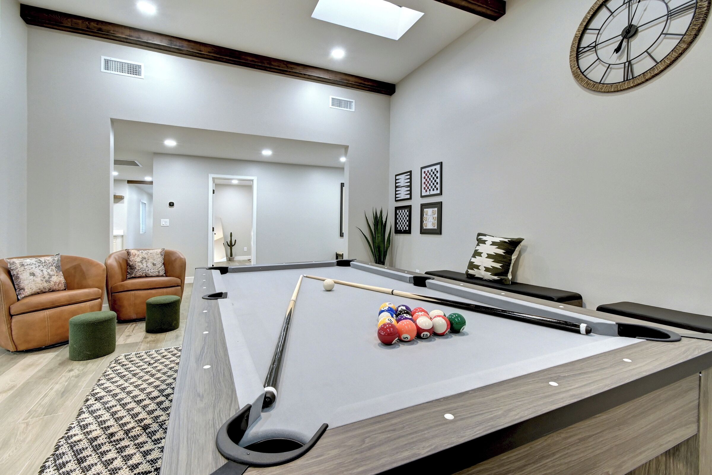 A pool table with balls, a clock, and a sofa in a room with a modern design.