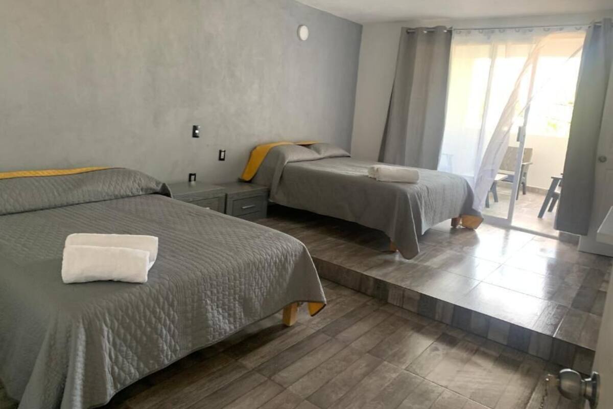 Hotellihuone, jossa on kaksi sänkyä, pieni pöytä ja liukuovi parvekkeelle.