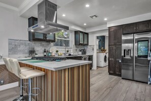 A modern kitchen with a central island, stainless steel appliances, and a built-in oven. - Serene 2BR Valley Glen Oasis: Private Yard, & BBQ (Los Angeles)