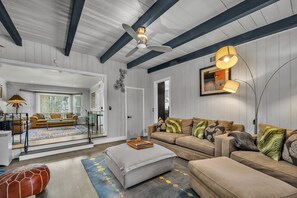 A spacious living room with a large sofa, a coffee table, and a ceiling fan. - Serene 2BR Valley Glen Oasis: Private Yard, & BBQ (Los Angeles)