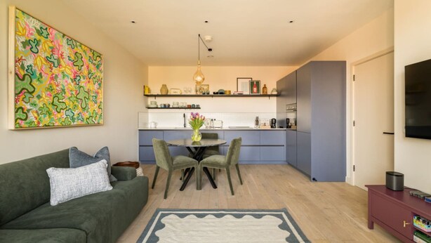 A modern living space with a sofa, a dining table with chairs, a kitchen area, and a TV on a stand. - Balham Modern - Stylish 1bed Flat With Balcony (Moffat)