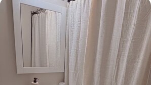 Un baño con inodoro, lavamanos, espejo y cortina de ducha.