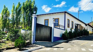 Un bâtiment d’un seul étage, avec une façade blanche, des ornements bleus et un portail noir.