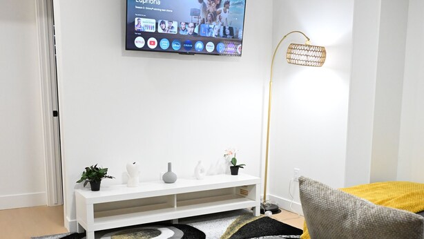 En stue med fjernsyn, sofa, sofabord og et konsolbord med pynt.