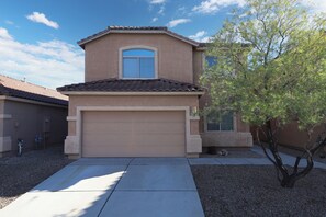 A two-story house with a beige facade, a brown roof, and a garage door. - Spacious 4-bedroom house with office and loft in fabulous Tucson. (Tucson)