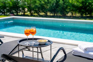A poolside setting with two glasses of orange beverage, a bowl of snacks, and a folded towel. - Villa Terris Pool & Jacuzzi, Labin, Croatia (Labin)
