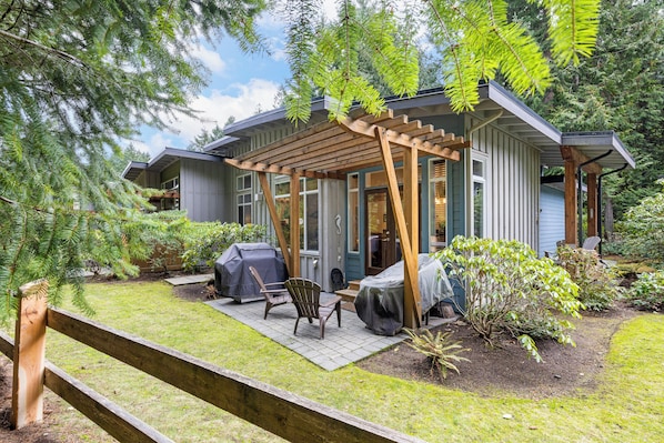 A house with a covered patio, outdoor furniture, and a grill.