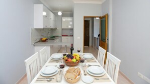 Comedor con una mesa dispuesta para cuatro, frutero, copas de vino y pan.