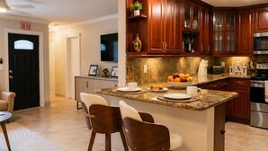 A kitchen with wooden cabinets, a granite countertop, and a built-in oven. - Luxury Pool Oasis • 5 Min to Beach • Modern Retreat (Hallandale Beach)