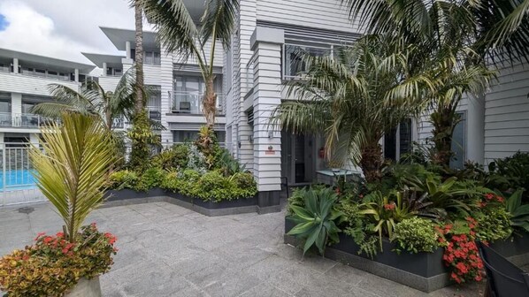A multi-story building with balconies, surrounded by lush greenery and a swimming pool. - Paihia by the Sea (Paihia)
