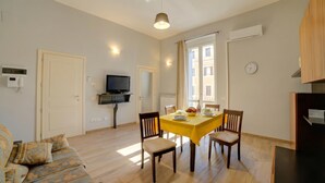 A living room with a sofa, dining table, chairs, a TV, and a ceiling fan. - Archi Home - Apartment with Balcony in Central Lecce, Lecce, Italy (Lecce)